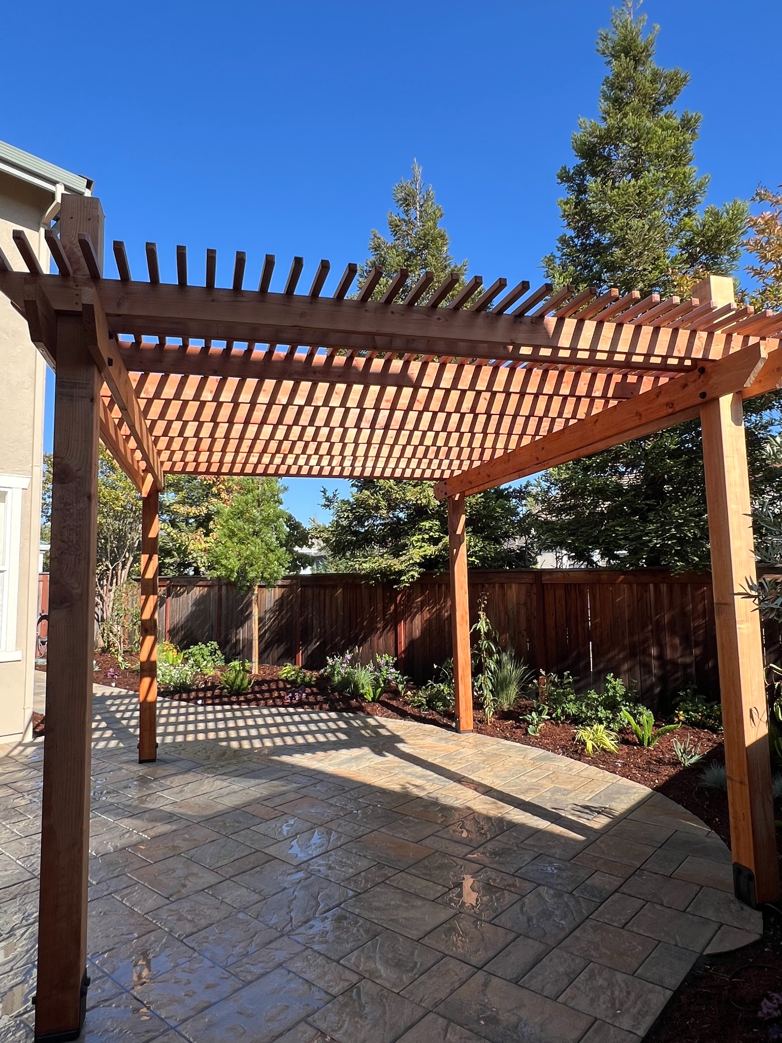 Completed redwood pergola, paver patio and garden installation by RJ Landscape